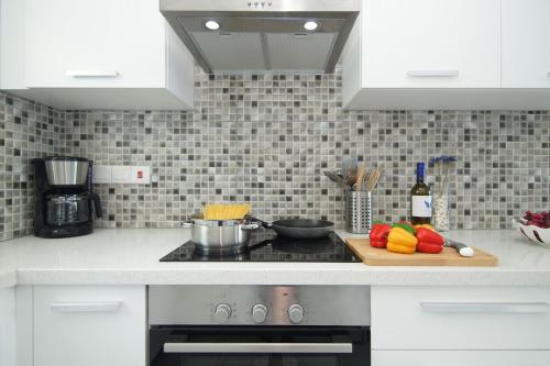 Una cocina con gabinetes blancos y una tabla de cortar con verduras. en Villa Levandini, en Protaras
