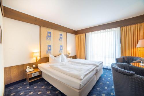 una habitación de hotel con una cama grande y una silla en City Club Hotel en Oldenburg