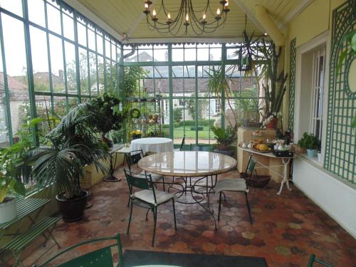 a conservatory with a table and chairs in a room with windows at Clos Saint Nicolas in Neauphle-le-Château