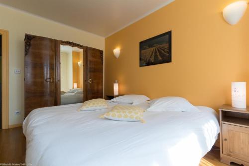 a bedroom with a large white bed with two pillows at Les Meix sous le Château in Meursault