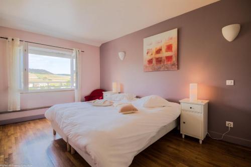 a bedroom with a large white bed and a window at Les Meix sous le Château in Meursault