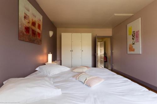 a large white bed with two pillows on it at Les Meix sous le Château in Meursault