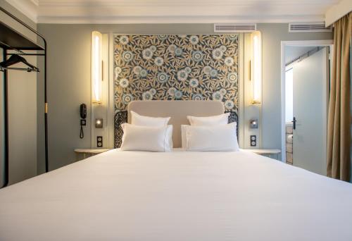 a bedroom with a large white bed with two pillows at ELSA, Hôtel Paris in Paris