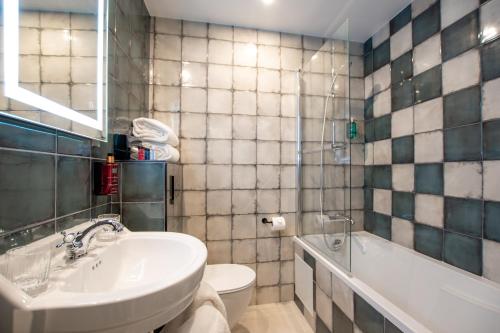 a bathroom with a sink and a toilet and a tub at ELSA, Hôtel Paris in Paris