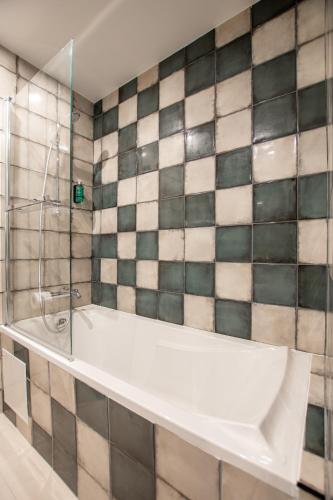 a white bath tub in a bathroom with tiled walls at ELSA, Hôtel Paris in Paris