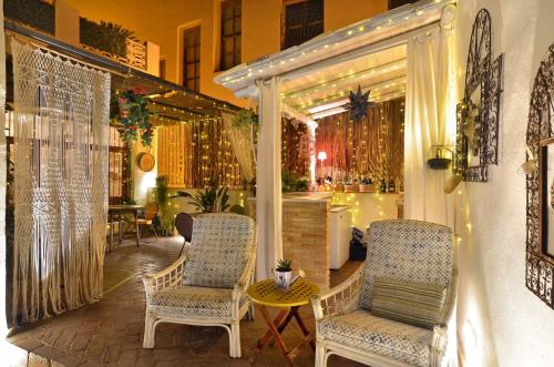 two chairs and a table on a porch with lights at La Casa de los Coy in Mula