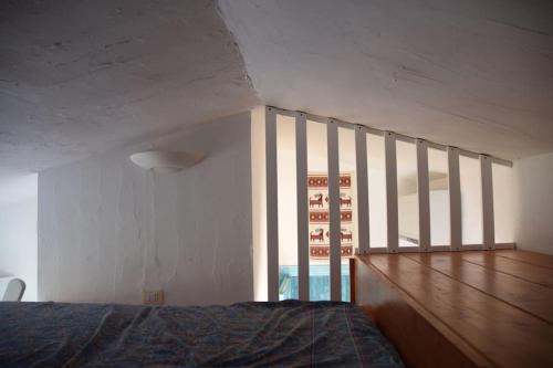 a bedroom with a bed and a large window at Appartamento in villa con ampia terrazza di 27m2 in Chia