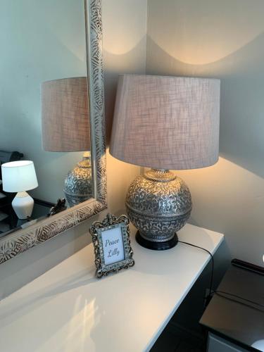 a lamp on a table with a clock and mirrors at Peace Lily Garden Cottage in George