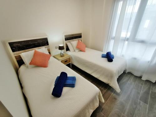 2 Betten in einem Zimmer mit blauen Kissen darauf in der Unterkunft Ap MAJORERO CALETA in Caleta de Fuste