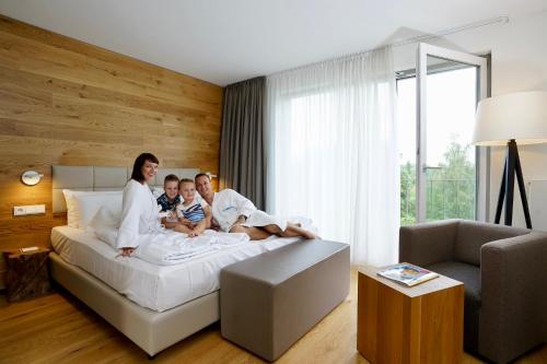 a family sitting on a bed in a bedroom at WONNEMAR Resort-Hotel in Wismar