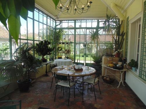 a conservatory with a table and chairs in a room with plants at Clos Saint Nicolas in Neauphle-le-Château