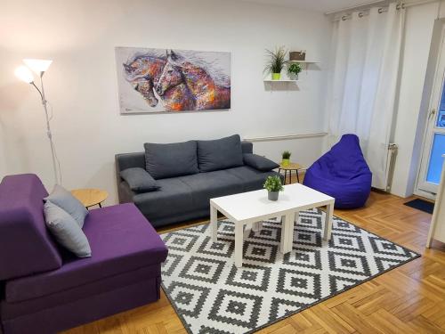 a living room with two purple couches and a table at Klara 23 in Tošin Bunar