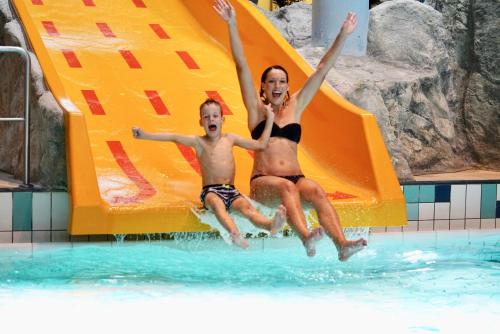 a boy and a girl are jumping on a slide in the water at WONNEMAR Resort-Hotel in Wismar