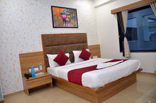 a bedroom with a large bed with red pillows at Hotel Newyork Inn in Anand