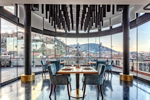 a dining room with a table and chairs and large windows at Tiflis Palace in Tbilisi City