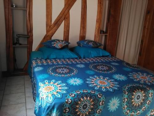 a bed with a blue comforter and pillows on it at Chambre d'Hôtes des P'tits Bonheurs in Dosches