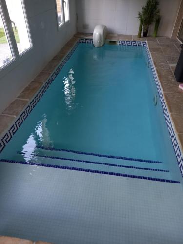 a large swimming pool with blue water in a room at La villa de Fleury in Fleury