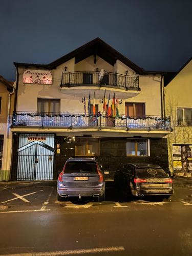 two cars parked in a parking lot in front of a building at Casa Floraly in Braşov