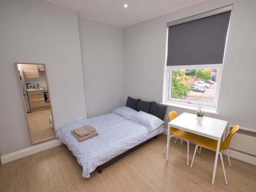 a bedroom with a bed and a table and a window at Stunning property fully refurbished in Birmingham
