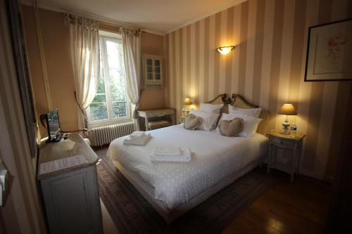 a bedroom with a large white bed with a window at LA CHASSE ROYALE in Plailly