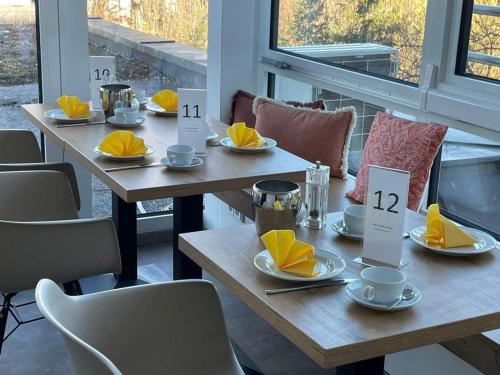 two wooden tables with yellow napkins and cups on them at Parkhotel Leiser in Planegg