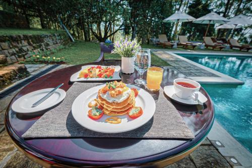 a table with pancakes and drinks next to a pool at The Lavender House by Reveal in Kandy