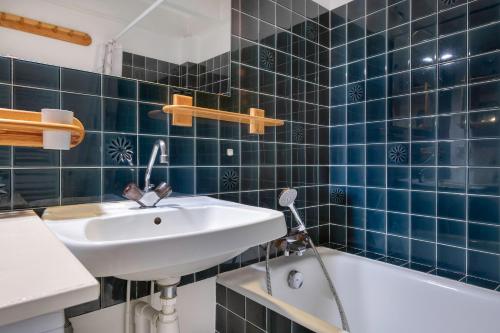 La salle de bains est pourvue de carrelage bleu, d'un lavabo et d'une baignoire. dans l'établissement Appartement accueillant pour 4 personnes, a quelques metres de la plage, à Saint-Gildas-de-Rhuys