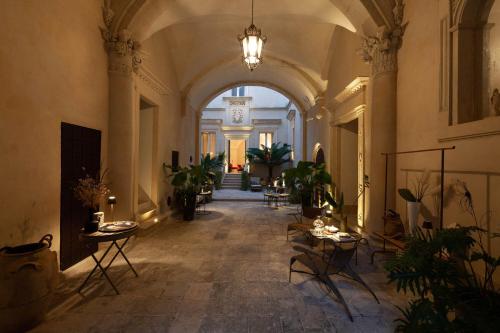 a hallway with tables and potted plants in a building at Palazzo Maresgallo Suites & SPA in Lecce