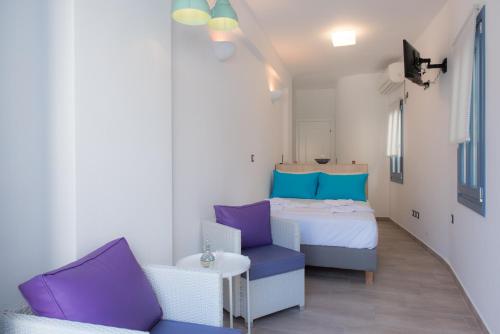 um pequeno quarto com uma cama e uma cadeira em BLUE Seaside Studio em Sifnos