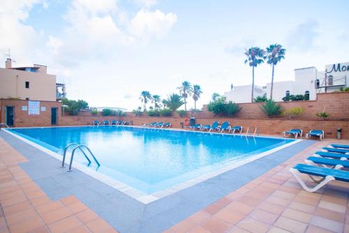a large swimming pool with chairs in a resort at 2BR Home next to Esquinzo Beach - Terrace in Pájara