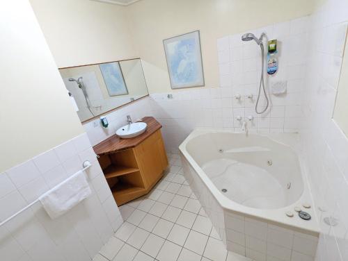 a white bathroom with a tub and a sink at Homestead Motor Inn & Apartments in Bendigo