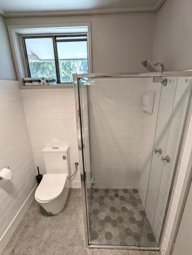 a bathroom with a toilet and a glass shower at Homestead Motor Inn & Apartments in Bendigo
