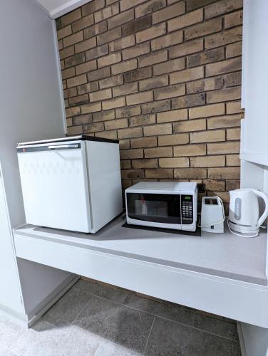 a microwave on a counter next to a brick wall at Homestead Motor Inn & Apartments in Bendigo