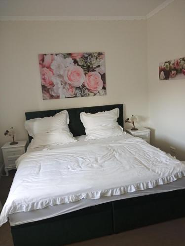 a bed with white sheets and pink roses on the wall at Boutique-Hotel Villa Rosali in Hamburg