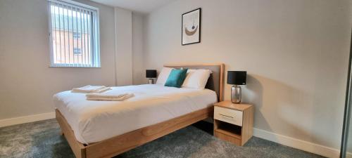 a bedroom with a bed and a night stand with a lamp at Seven Living Residences Slough - City Apartments, Free Parking in Slough