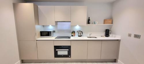a white kitchen with a sink and a microwave at Seven Living Residences Slough - City Apartments, Free Parking in Slough