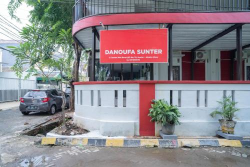 a sign in front of a building with a car at RedDoorz Plus near ITC Cempaka Mas 2 in Jakarta