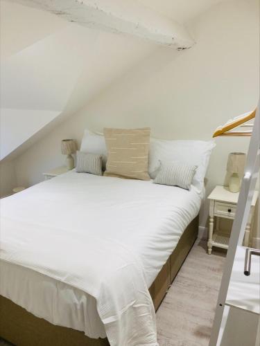 a large white bed with white sheets and pillows at The Bluebell Porthmadog in Porthmadog