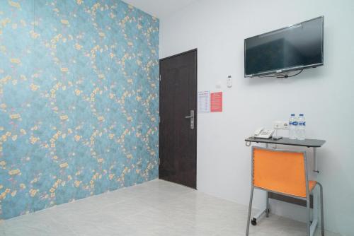a room with a desk and a tv on a wall at RedDoorz Plus near ITC Cempaka Mas 2 in Jakarta