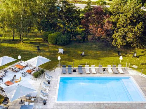 - une vue sur la piscine bordée de chaises et de parasols dans l'établissement Novotel Beaune, à Beaune
