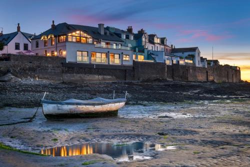 a boat sitting in the water in front of a house at The Royal George in Appledore