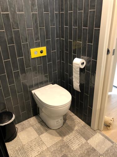 a bathroom with a toilet and a tiled wall at STUDIO RETREAT BY THE BEACH in Rye