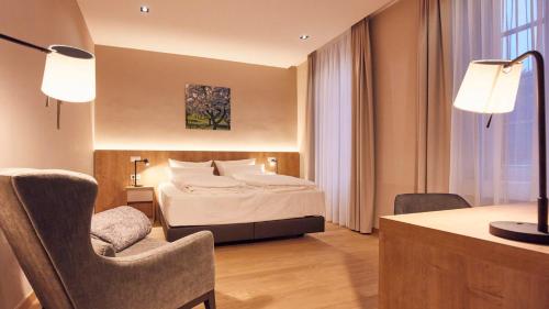 a hotel room with a bed and a desk and a chair at Seehotel Maria Laach in Maria Laach