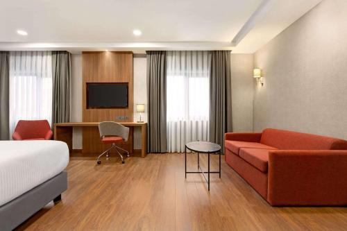 Habitación de hotel con sofá y TV en Ramada by Wyndham Adiyaman, en Adıyaman