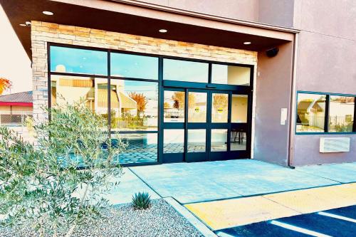 a building with large glass doors with a swimming pool at Ramada by Wyndham Modesto Yosemite Area in Modesto