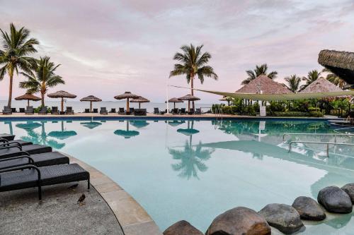 丹那勞島的住宿－Club Wyndham Denarau Island, Trademark Collection by Wyndham，一座棕榈树和遮阳伞的游泳池