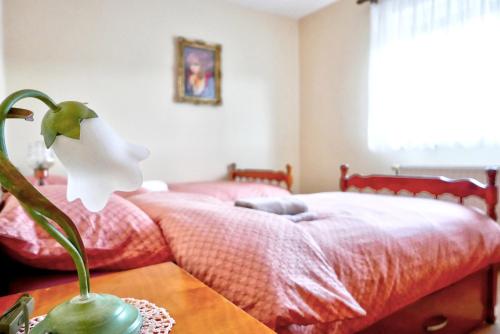 a bedroom with a bed and a flower on a table at Apartman Verona in Ilok