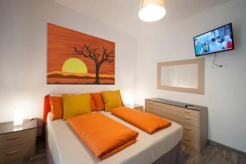 een slaapkamer met een bed met oranje lakens en een schilderij aan de muur bij Cipriani 5 RivieraHoliday in Pietra Ligure