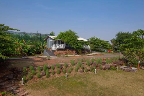 a garden with trees and a house in the background at StayVista's Volendam Acres - Lake-View Villa with Pool, Amphitheatre & Turf in Wādhiware