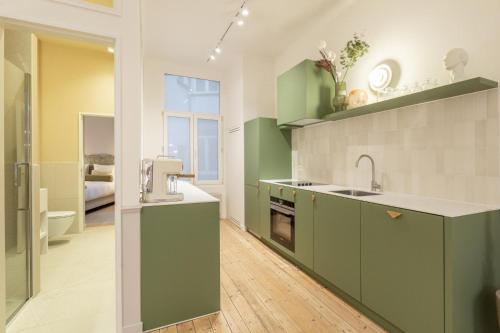 una cocina con armarios verdes y fregadero en Le Marnix, en Amberes